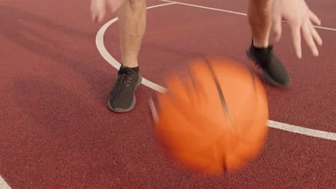 Legs man practicing ball skills by rolling a basketball between his legs on an Stock Footage 166537079