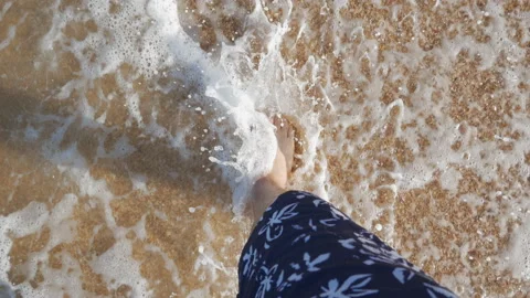 The legs of a man walking along the ocean step on the wet sand of the coastline Stock Footage 119688412