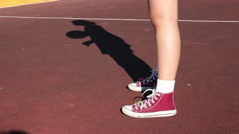 Legs of player in red sneakers bouncing a basketball on a red outdoor court with Video stock 315429094