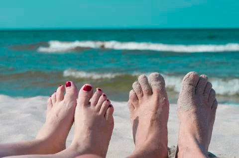 Legs of relaxing couple sitting on a sea front. Stock Photos