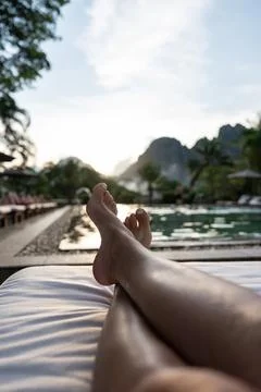 Legs relaxing by pool watching beautiful mountain sunset Stock Photos