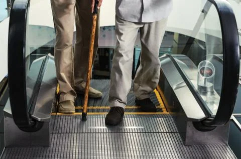 Legs of two men at the exit from the escalator. Stock Photos