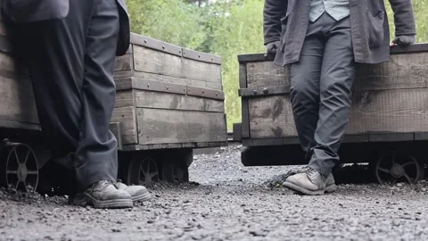 Legs of Two Men in Old Work Clothes and Boots Resting Near the Coal Wagons Stock Footage 258150450