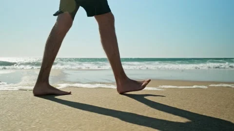Legs of a walking young man on a sandy beach against the ocean Stock Footage 303585031