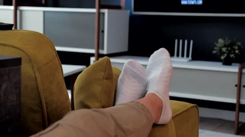Legs in white socks lie in front of the TV. Close-up on his feet. Cozy Stock Footage 140733182