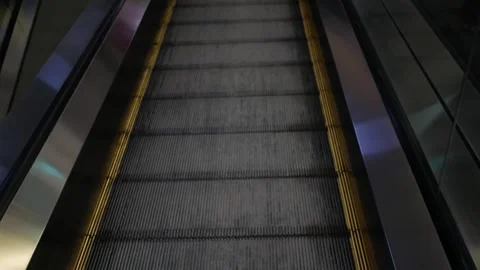 Legs of a woman using a moving down escalator in the mall. Pair in the shoes sne Stock Footage 274076894