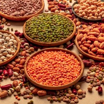 Legumes assortment on a brown background. Lentils, soybeans, chickpeas, red Stock Photos