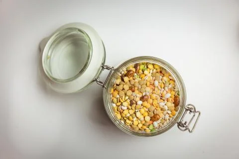 Legumes in glass container, topdown view, bulk, white background Stock Photos