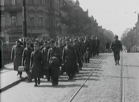 LEIPZIG - 1945: Liberated prisoners — Column on a cobbled tram-tracked boulevard Stock Footage 342919612