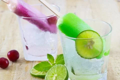 Lemon and cherry popsicles homemade in glass with ice on wood 库存照片