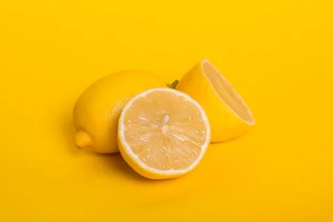 Lemon and half a lemons on a yellow background. Ripe tropical fruit. Stock Photos