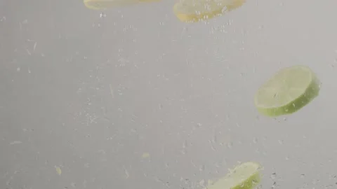 Lemon and lime slices dropping into water in slow motion 库存影片 220755815