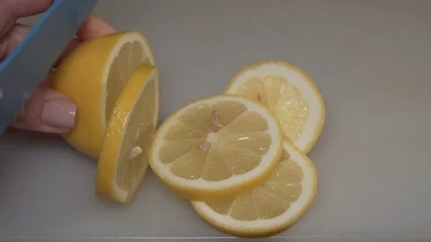 Lemon being cut by a woman's hand Stock Footage 84614679