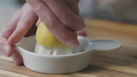 Lemon being pressed and juice squeezed out in real time with fruit in Stock-Footage 336588672