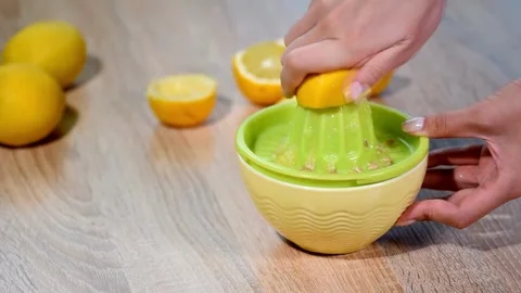 Lemon being pressed and juice squeezed out in real time with fruit in Stock-Footage 336588689