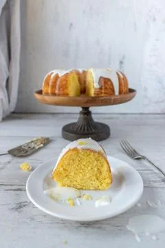 Lemon bundt cake with white glaze on cake stand with cake slice Foto stock