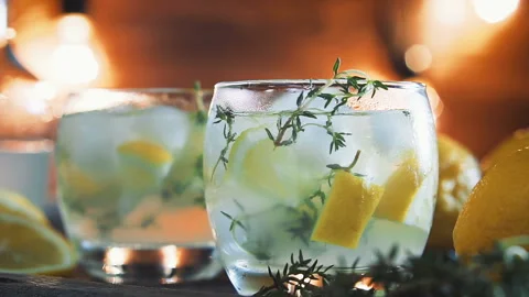Lemon cocktail with thyme and ice on dark rustic background, close-up. Stock Footage 88436372