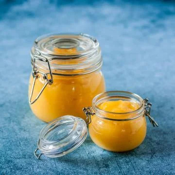 Lemon Curd in Jars over Blue Background Stock Photos