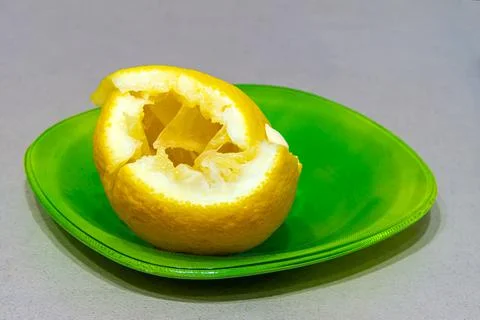 Lemon, cut and poorly squeezed, lies on a green plate Stock Photos