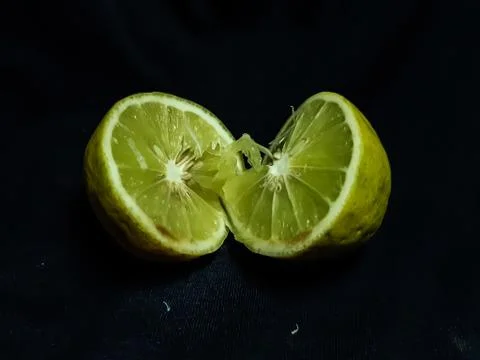 A Lemon is cut in the middle and placed on a black background. Stock Photos