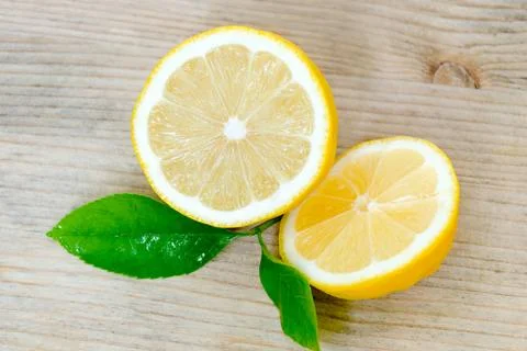 Lemon, cut into two halves with leaves on a wooden background. Stock Photos