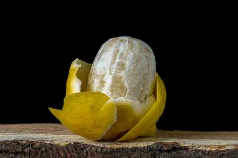 Lemon on a dark background. A peeled lemon lies in a peel on a black background. Stock Photos
