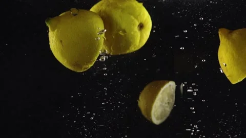 Lemon dropped in water with splash and air bubbles isolated over black Stock Footage 293086091