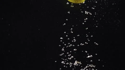Lemon dropping or falling in clear water with bubbles on back background, copy Stock Footage 293085998
