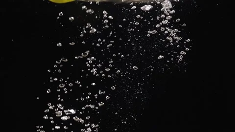 Lemon dropping or falling in clear water with bubbles over black background, Stock Footage 293086011