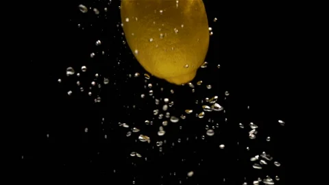 Lemon drops into water in slow motion on a black Stock Footage 137166379