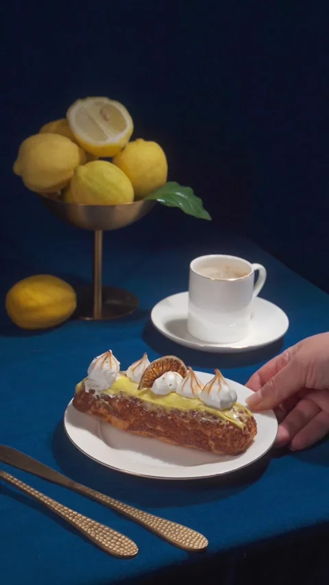 Lemon Eclair Dessert and Coffee Serving on Cafe Table with Fresh Lemons and Stock Footage 335422278