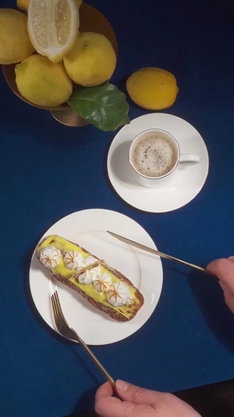 Lemon Eclair Dessert and Coffee Serving on Cafe Table with Fork and Cup Close Up Stock Footage 335422309