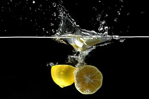 Lemon falling into water creating movement, motion and splashes Stock Photos
