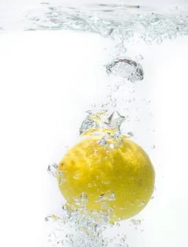 Lemon falling into water - studio isolated. Stock Photos