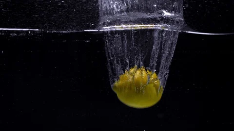 Lemon falls in the water in slow motion. Isolated on black background. Close up Video stock 123712215