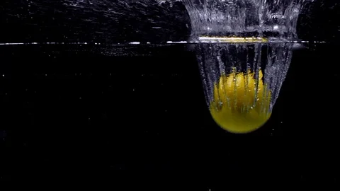 Lemon falls in the water in slow motion. Isolated on black background. Close up Video stock 123712329