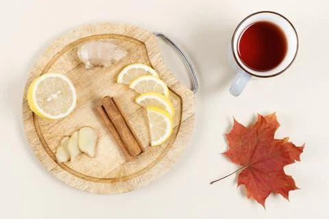 Lemon, ginger root and cinnamon sticks on wooden plate. Cup of tea and maple  Stock Photos
