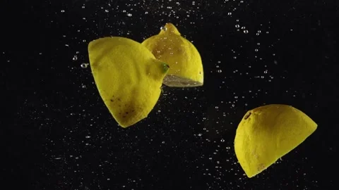 Lemon halves dropping or falling in clear water with bubbles on back background Stock Footage 293086070