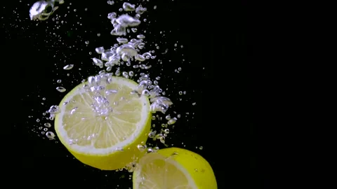 Lemon halves falling into water with air bubbles in slow motion Stock Footage 139370592