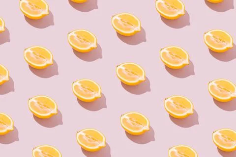 Lemon halves pattern on a pale pink background. Sunny yellow summer fruit. Stock Photos