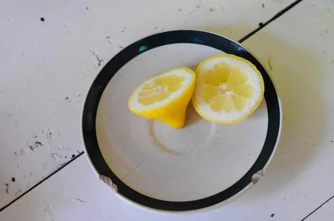Lemon halves on rustic plate add vibrant color to a neutral background Stock Photos