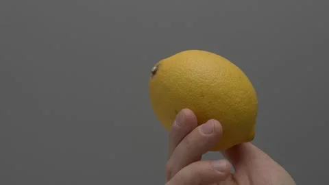 Lemon in hand on a gray background. Stockbeeldmateriaal 265758472