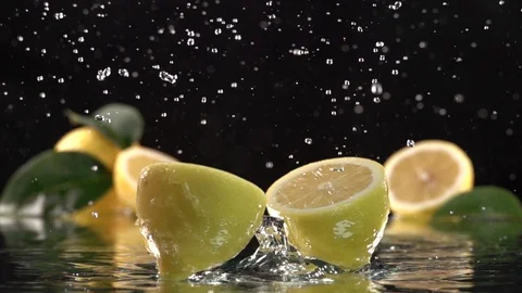 Lemon hits orange juice surface and splits into halves. Slow motion shot. Close Stock Footage 89564889