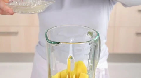 Lemon juice being added to mango pieces in a blender Video stock 24657341