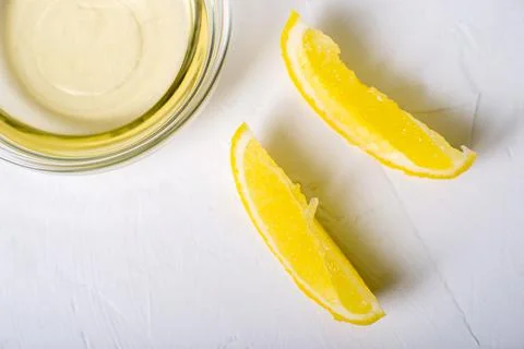 Lemon juice in a bowl. Essence. Lemon slices. White background. Stock Photos