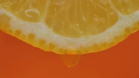 Lemon juice flows from pulp and drips on orange background, macro video, word Stock Footage 220264513