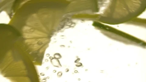 Lemon lime slices floating water slow motion close up video. Fruit rotation Stock Footage 83932390