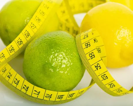 Lemon with lime on the white surface of the table with a tape measure for mea Stock Photos