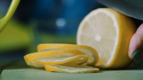 From a lemon lying on a table a knife is cut off with a knife. Stock Footage 76988821