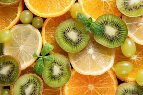 Lemon, orange slices,  mint, sprig , green grapes, kiwi, on a grey background Stock Photos